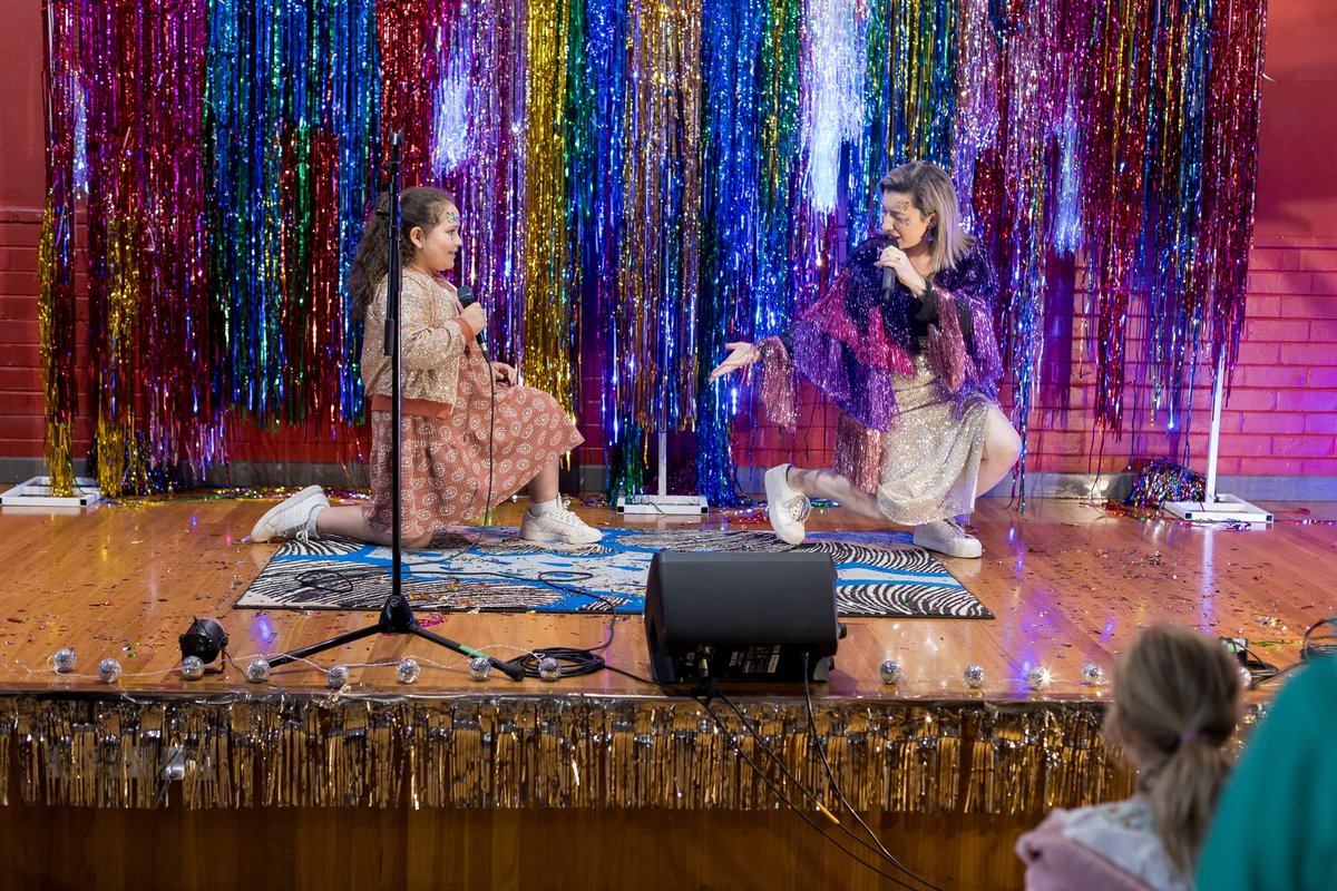Student and teacher performing together on a colourful tinsel stage